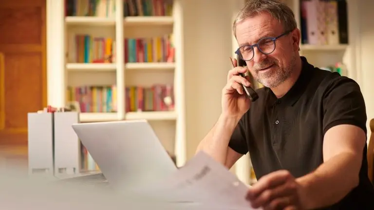 Building Passive Income Streams Man with phone in hand in front of laptop