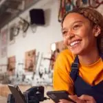 digitale produkte für offline profis enhance your service sell digital products to clients smiling business owner woman in her shop with smart phone in hand