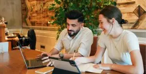 passive Einkommen Mythen sicheres Einkommen aufbauen realistisches passives Einkommen, passives Einkommen mit System, passives Einkommen ohne Social Media, Expertise zu Einkommen machen, digitale Produkte für Coaches, wissensbasiertes Einkommen, passives Einkommen für Dienstleister:innenpassive income myths man and woman sitting in office at table looking into laptop and ipad realistic passive income, system for passive income, passive income without social media, turn your expertise into income, digital products for coaches, knowledge-based income, passive income for service providers