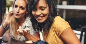 digitales-produkt-portfolio-aubauen Build your Digital Product Portfolio smartly. two young women sitting at table and are laughing