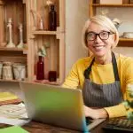 blockaden beim start digitaler produkte Female Business Owner smiling in camera and sitting at her desk in her flower shop Overcome Fears to start with Digital Products