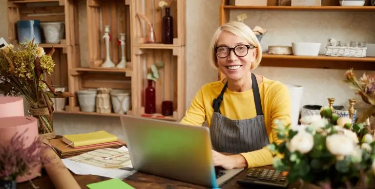 blockaden beim start digitaler produkte Female Business Owner smiling in camera and sitting at her desk in her flower shop Overcome Fears to start with Digital Products